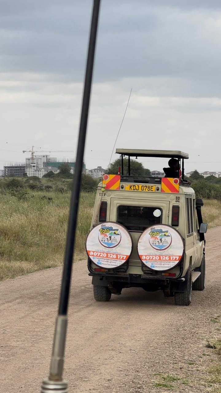 The Mama Toto safari vehicle driving a dirt track through open grassland